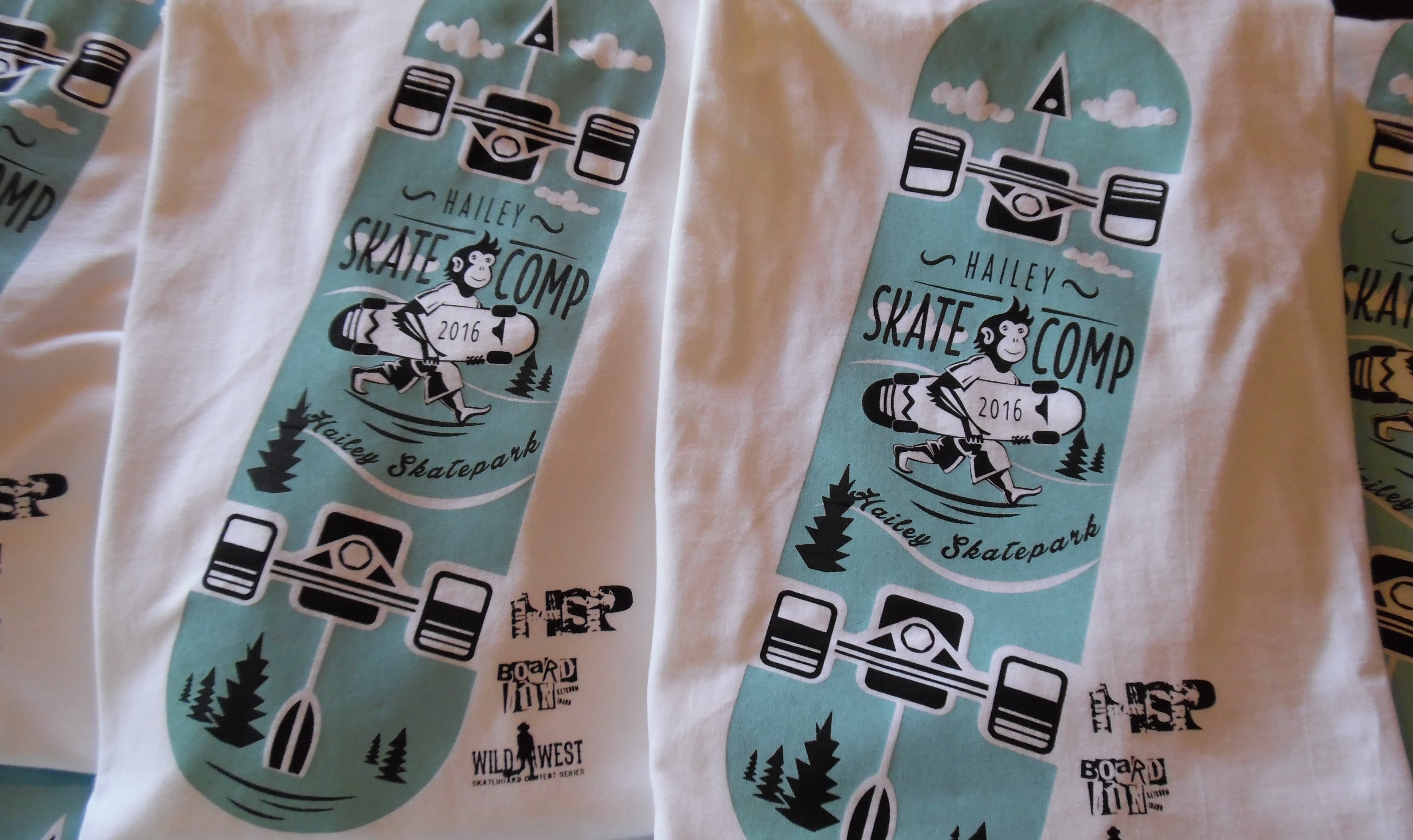 White t-shirts with teal graphic designs of skateboards and text on a white background